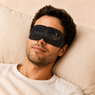 Man wearing Nyla Rest Steam Eye Mask lying on a beige pillow